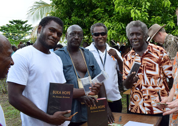Roviana men stand holding their new Bibles, the 'Buka Hope'