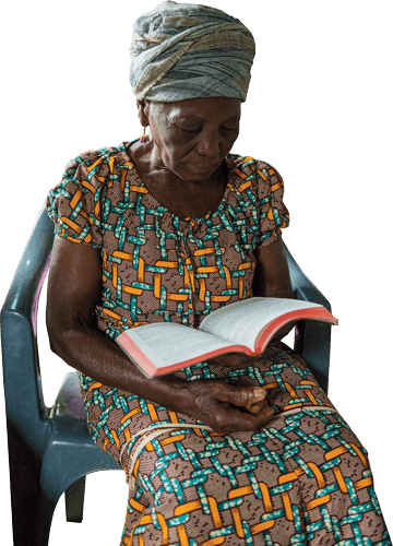 seated elderly woman reads the Bible in her language